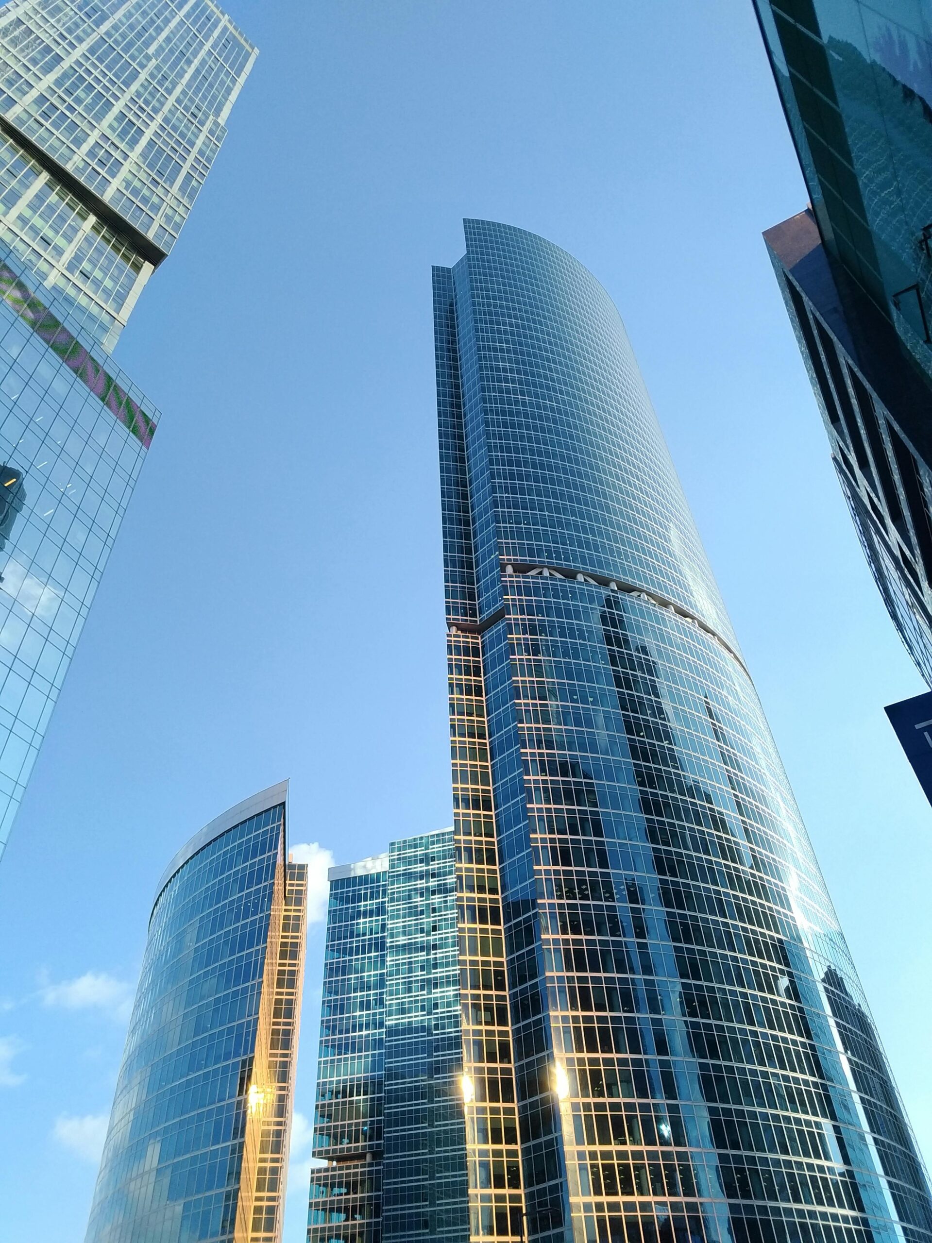 Futuristic skyscrapers with glass facades reflecting the sky in an urban setting.